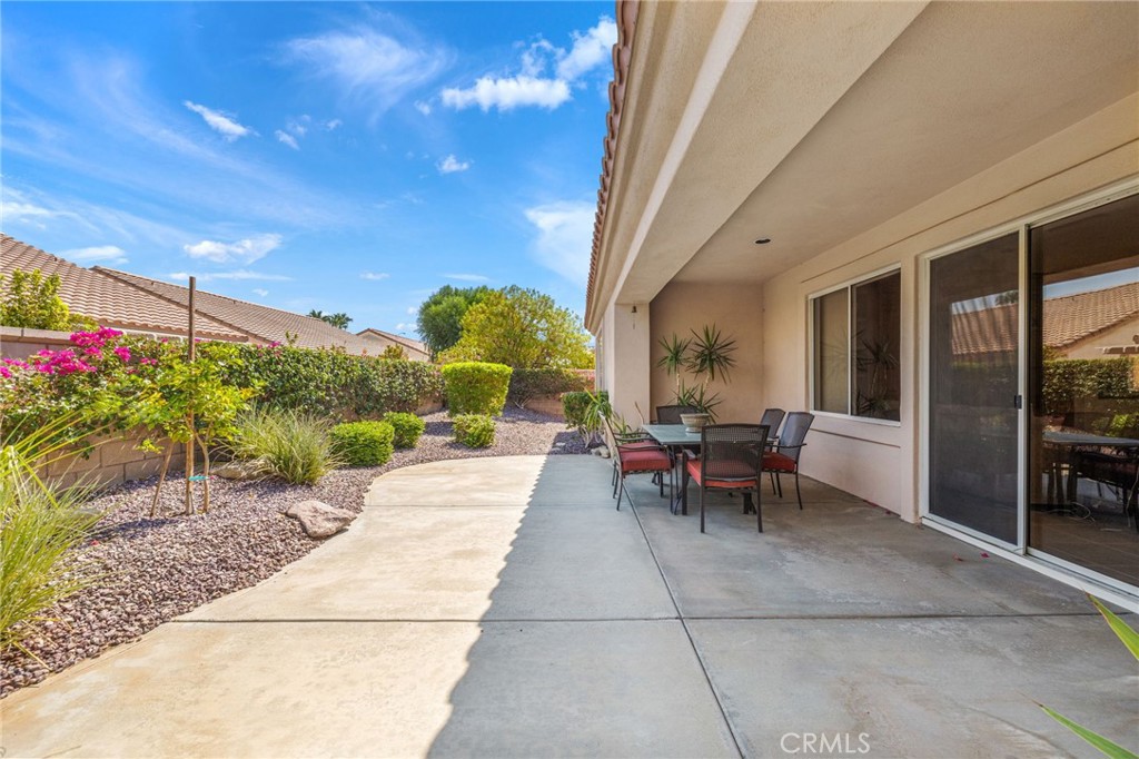 78770 Golden Reed Drive Palm Desert, CA 92211 - Photo 7 of 36 a view of a patio with dining table and chairs with plants and trees