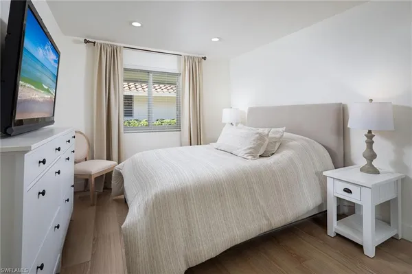 a bedroom with a bed and a flat tv screen on dresser