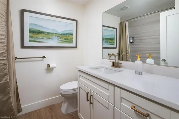a bathroom with a granite countertop sink a toilet and a window