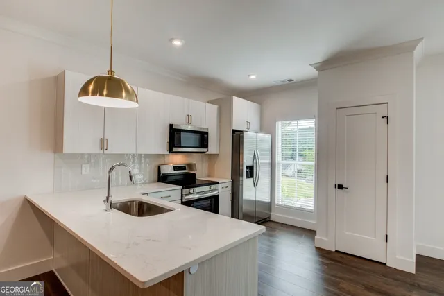 a kitchen with stainless steel appliances a sink a stove a refrigerator cabinets and a dining table