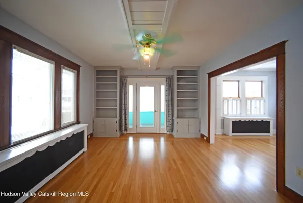 a view of an empty room with wooden floor and a window