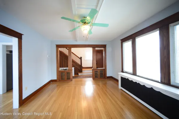 a view of an empty room with wooden floor and a window