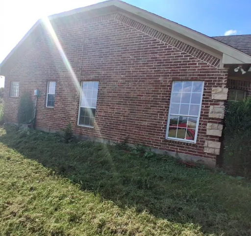 a brick house with lots of trees in front of it