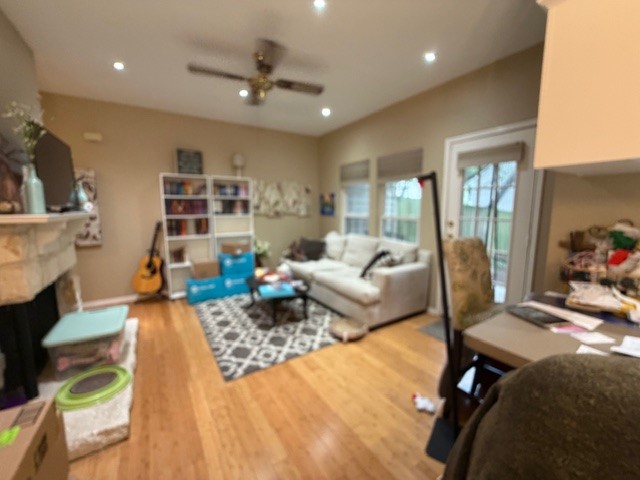 This living area features hardwood floors, recessed lighting, and a ceiling fan