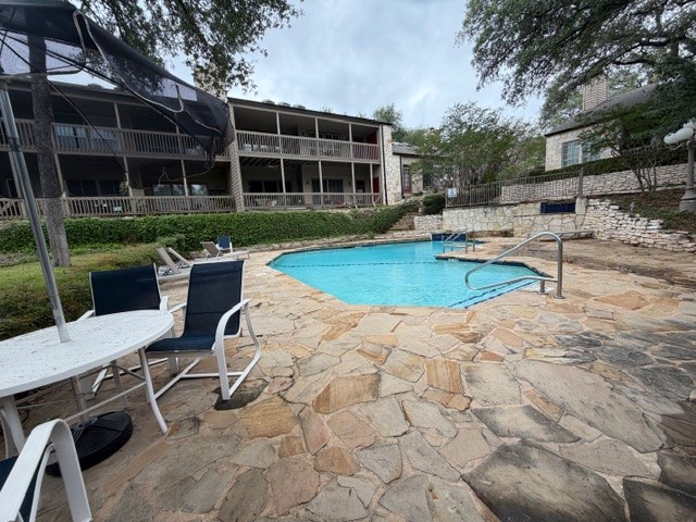 3809 Spicewood Springs Road, Unit 119 Austin, TX 78759 - Photo 14 of 14 The property features a swimming pool with stone decking, surrounded by lush landscaping and mature trees