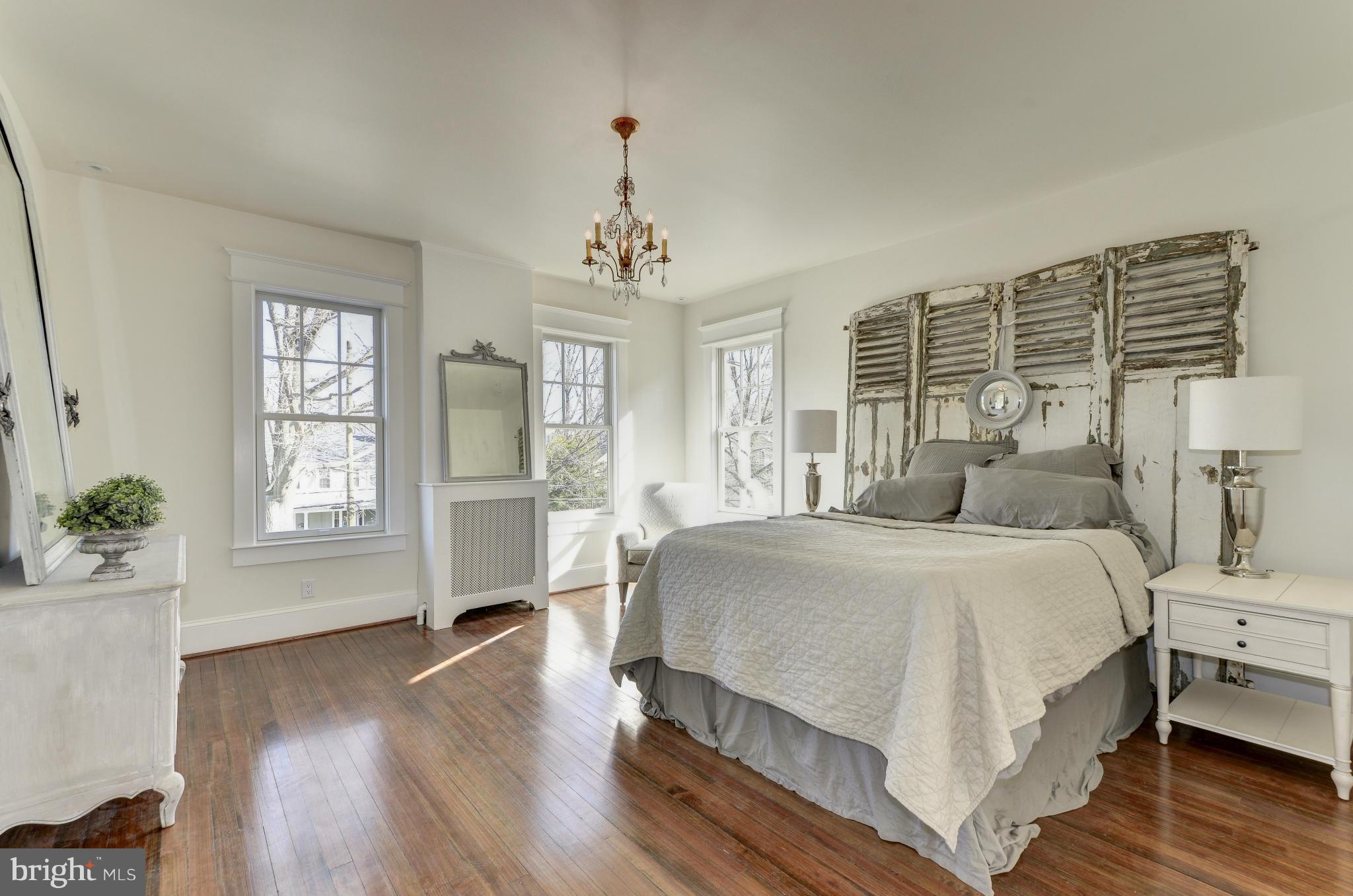 3816 Military Road Northwest Washington, DC 20015 - Photo 12 of 22 a spacious bedroom with a large bed and a chandelier