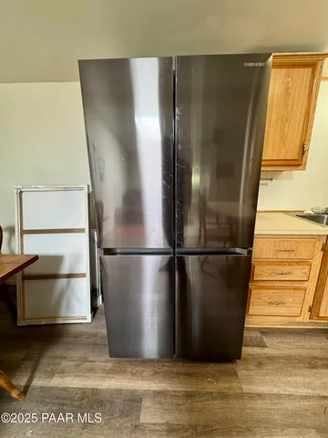 a view of a refrigerator in kitchen and an empty room