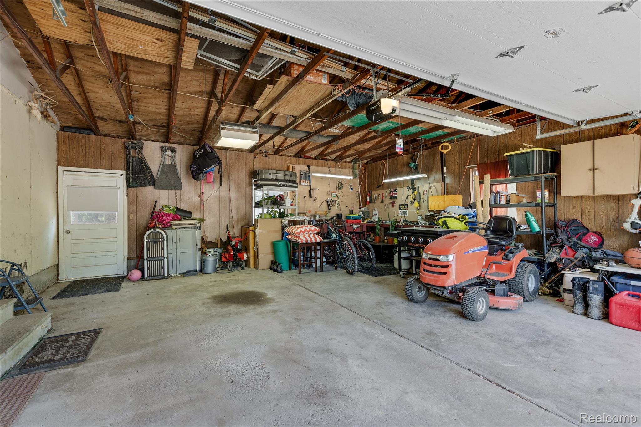 4497 Reid Road Swartz Creek, MI 48473 - Photo 23 of 31 Spacious garage with concrete flooring, exposed wood beam ceiling, and wood-paneled walls