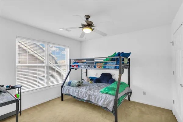 a bedroom with a bed a ceiling fan and a window