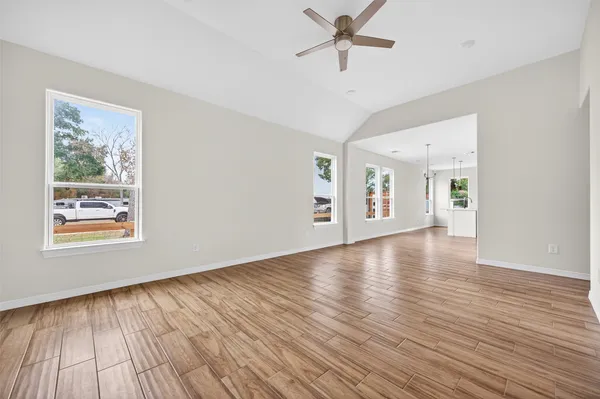 a view of an empty room with wooden floor and a window