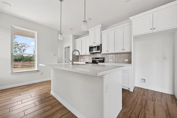 a kitchen with kitchen island granite countertop a sink cabinets and wooden floor