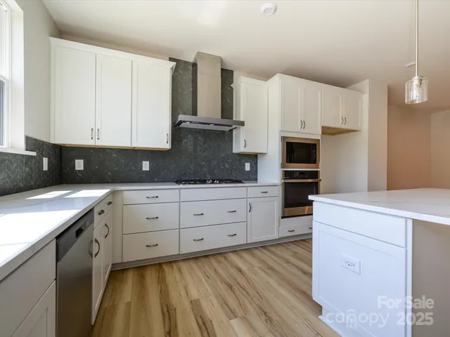 a kitchen with stainless steel appliances white cabinets and a refrigerator