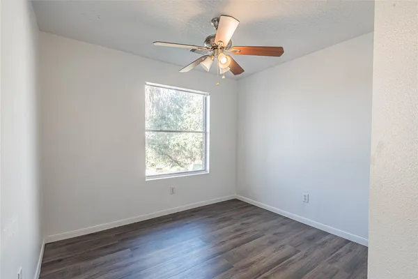 an empty room with wooden floor fan and windows