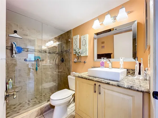 a bathroom with a granite countertop sink toilet and shower
