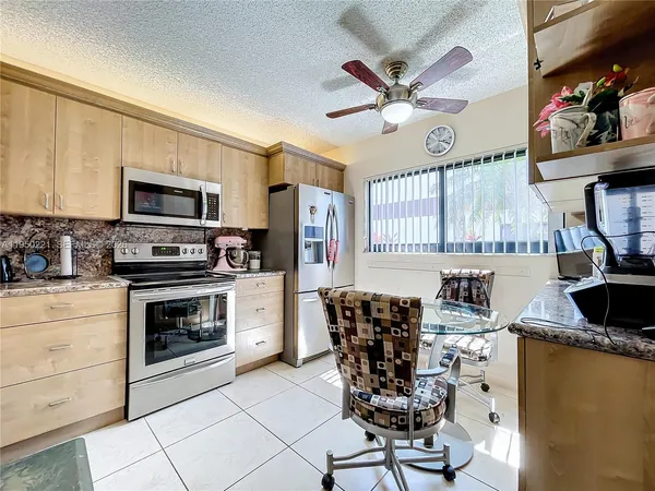 a kitchen with stainless steel appliances kitchen island granite countertop a stove top oven a sink a dining table and chairs with wooden floor