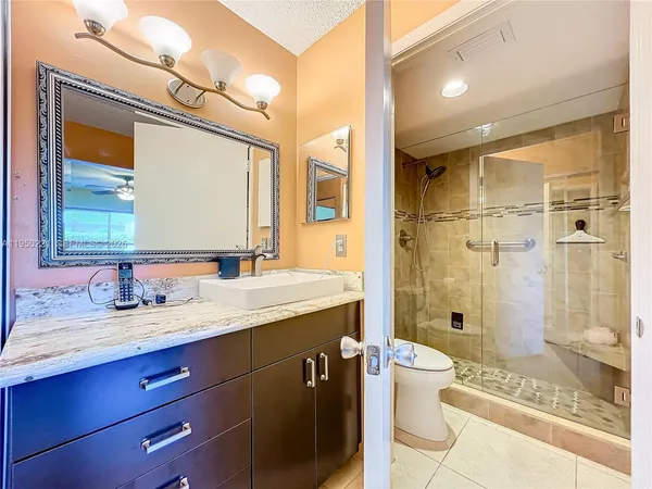 a bathroom with a granite countertop sink toilet a mirror and shower