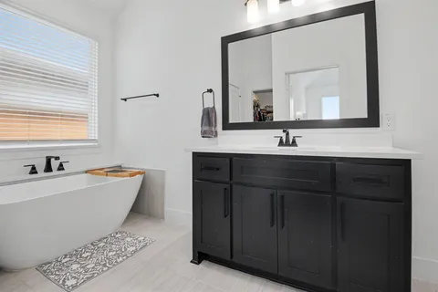 a bathroom with a bathtub a double vanity sink and mirror