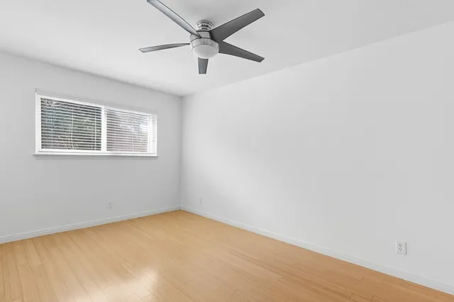 an empty room with a window and a fan
