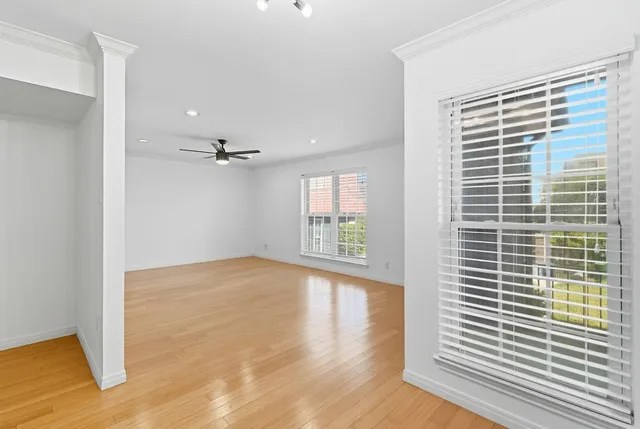a view of empty room with wooden floor and fan
