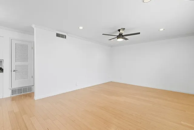 an empty room with ceiling fan and window