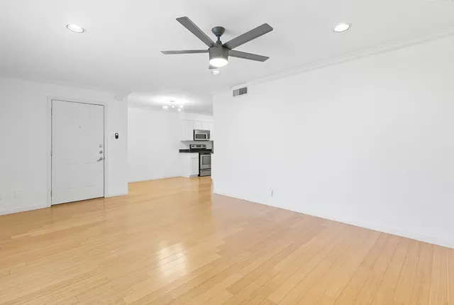 an empty room with wooden floor and ceiling fan