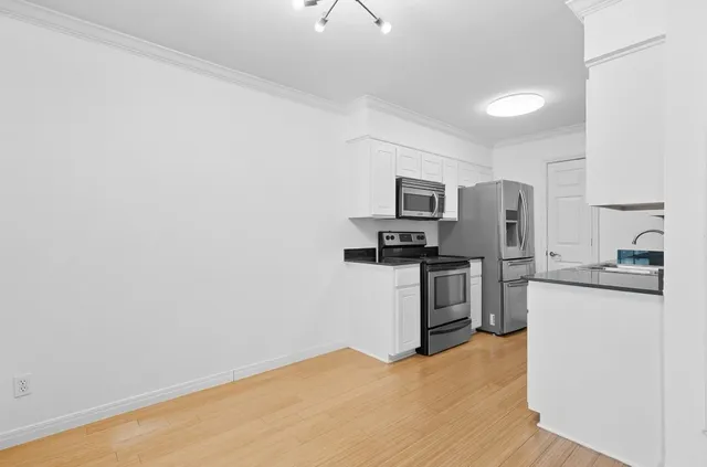 a kitchen with granite countertop white cabinets and stainless steel appliances