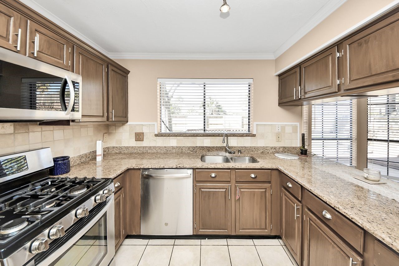 7607 Plum Tree Forest Circle Houston, TX 77095 - Photo 16 of 42 a kitchen with stainless steel appliances granite countertop a stove sink and cabinets