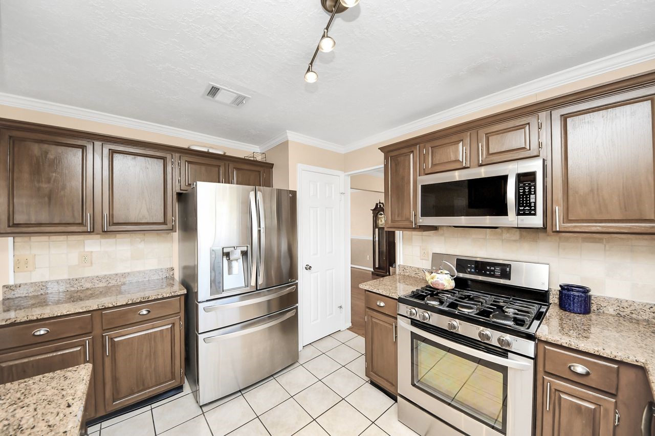 7607 Plum Tree Forest Circle Houston, TX 77095 - Photo 18 of 42 a kitchen with stainless steel appliances granite countertop a stove microwave and refrigerator