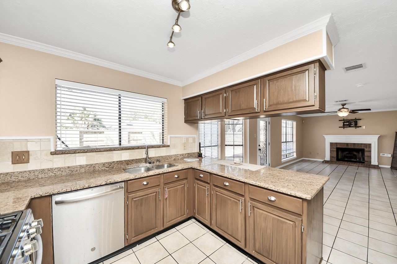 7607 Plum Tree Forest Circle Houston, TX 77095 - Photo 20 of 42 a kitchen with granite countertop a sink cabinets stainless steel appliances and a window