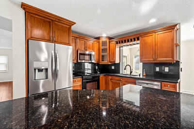 10056 Country Brook Road Boca Raton, FL 33428 - Photo 5 of 15 a kitchen with stainless steel appliances granite countertop a refrigerator a stove top oven and a sink with granite countertops