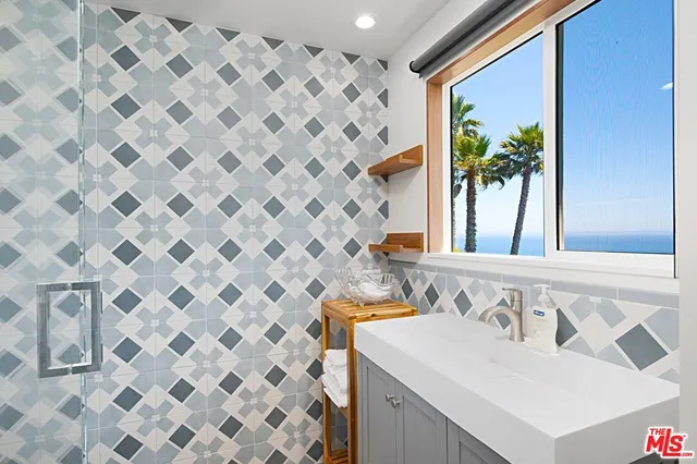a view of a patio with a table and chairs under an umbrella with a barbeque