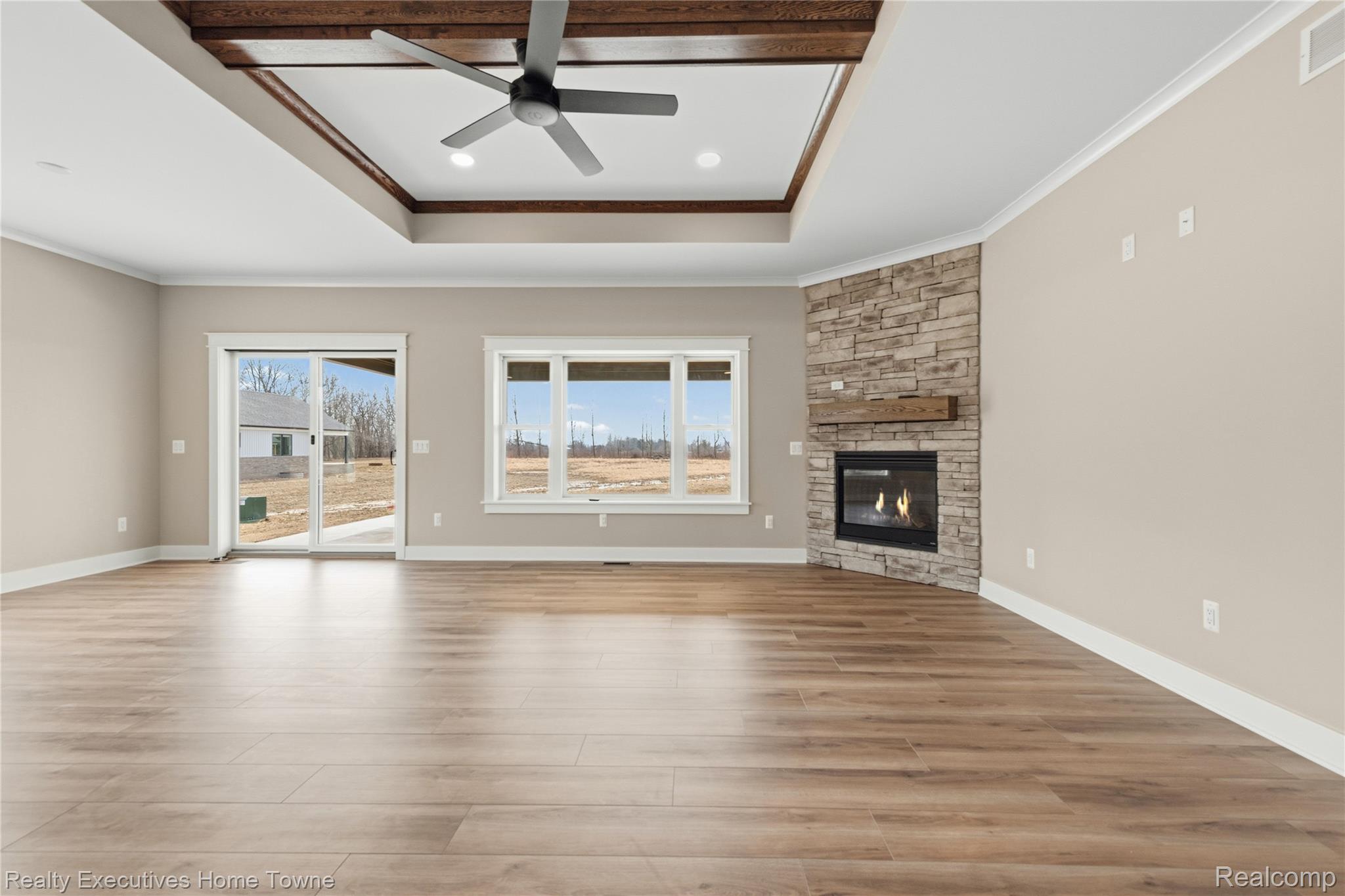 26850 Irwin Road Richmond, MI 48062 - Photo 8 of 47 Unfurnished living room with a ceiling fan, a stone fireplace, light wood-style flooring, and crown molding