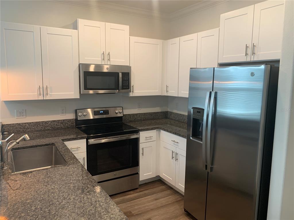 6930 Ripple Pond Loop Zephyrhills, FL 33541 - Photo 14 of 29 a kitchen with stainless steel appliances granite countertop a stove a refrigerator and a microwave