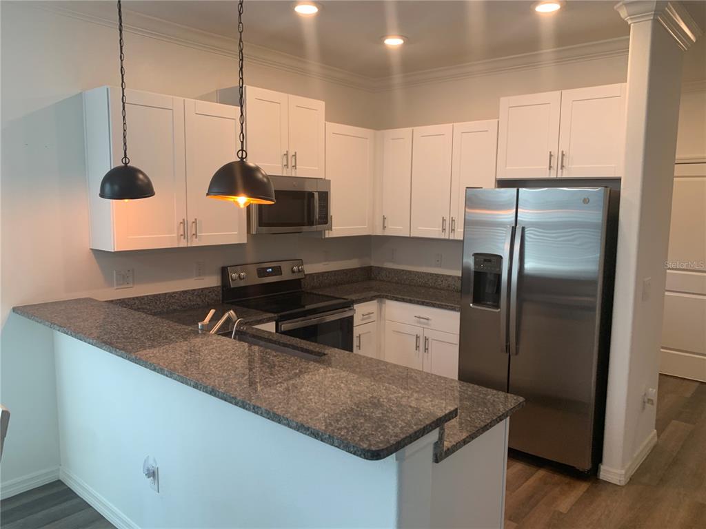 6930 Ripple Pond Loop Zephyrhills, FL 33541 - Photo 10 of 29 a kitchen with stainless steel appliances granite countertop a sink a stove and a refrigerator