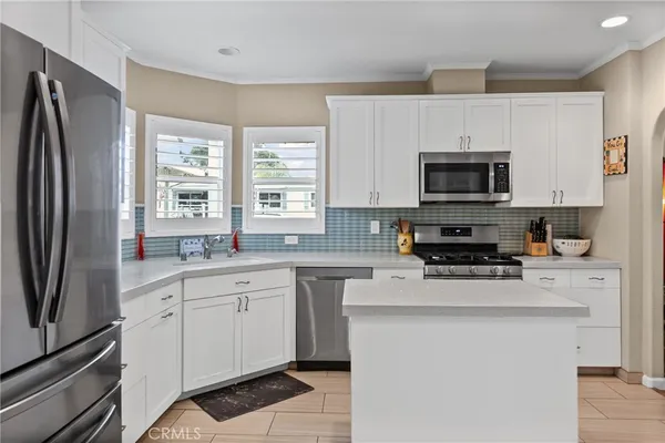 a kitchen with stainless steel appliances a sink cabinets and a window
