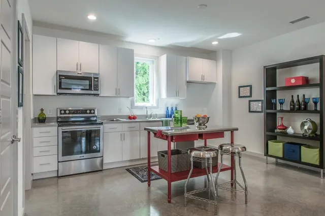a kitchen with stainless steel appliances a stove a sink a microwave a dining table and chairs