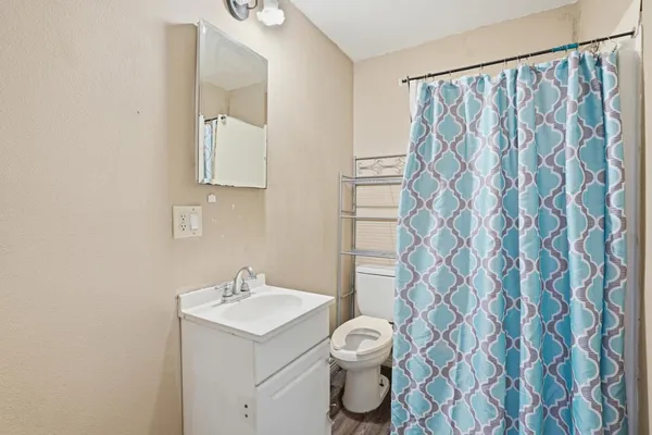 a white toilet sitting next to a white sink and a shower curtain