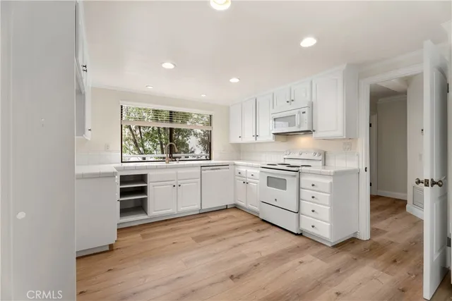a kitchen with a white stove top oven and white cabinets
