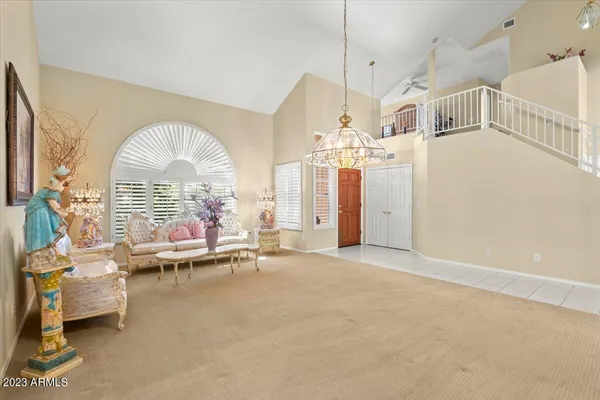 a living room with couches a dining table and a chandelier