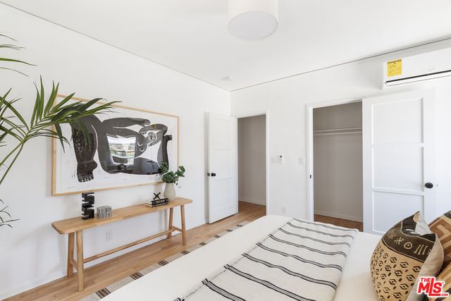 a bedroom with a bed and a potted plant on the dresser