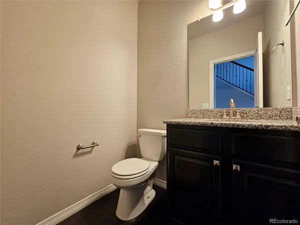 a bathroom with a granite countertop sink and a toilet