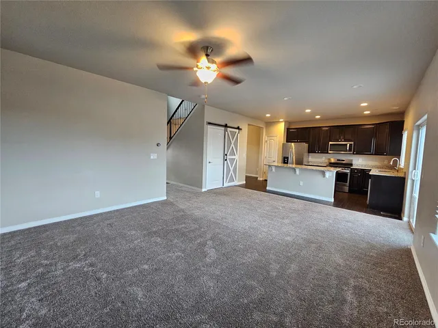 a view of a kitchen with a stove cabinets a ceiling fan and wooden floor