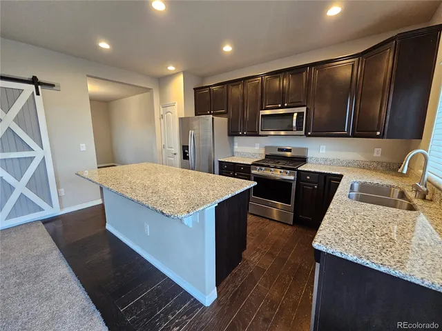 a kitchen with kitchen island granite countertop wooden cabinets a refrigerator and a sink