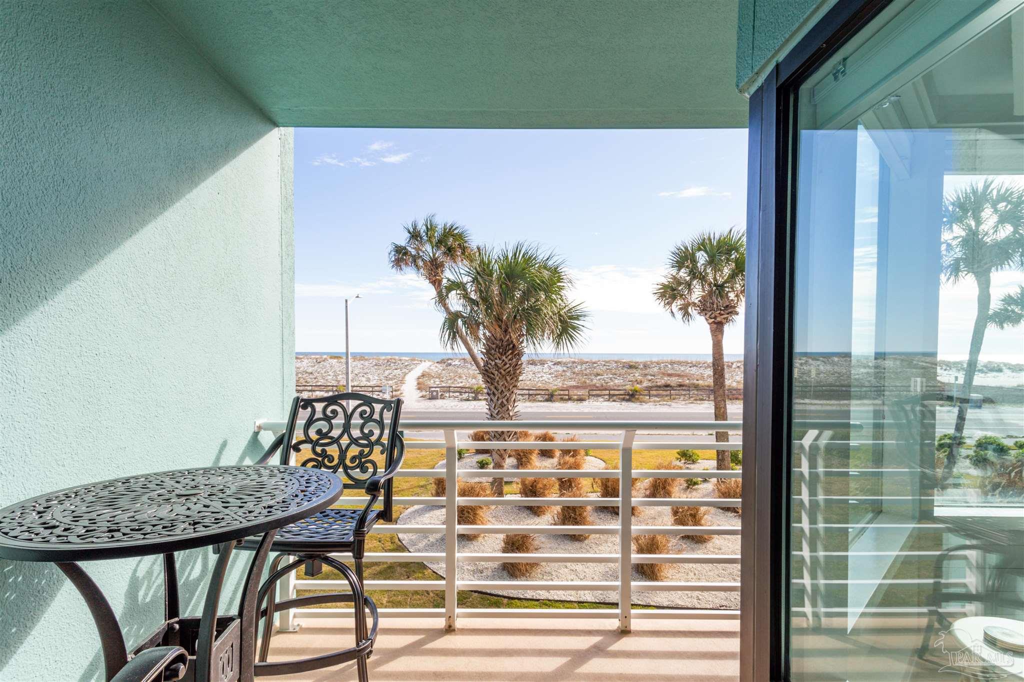 1390 Fort Pickens Road, Unit 116 Pensacola Beach, FL 32561 - Photo 20 of 37 a view of a balcony with a table and chairs