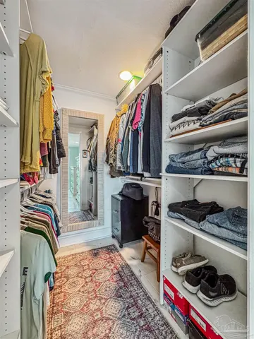 a view of walk in closet with clothes and shoes