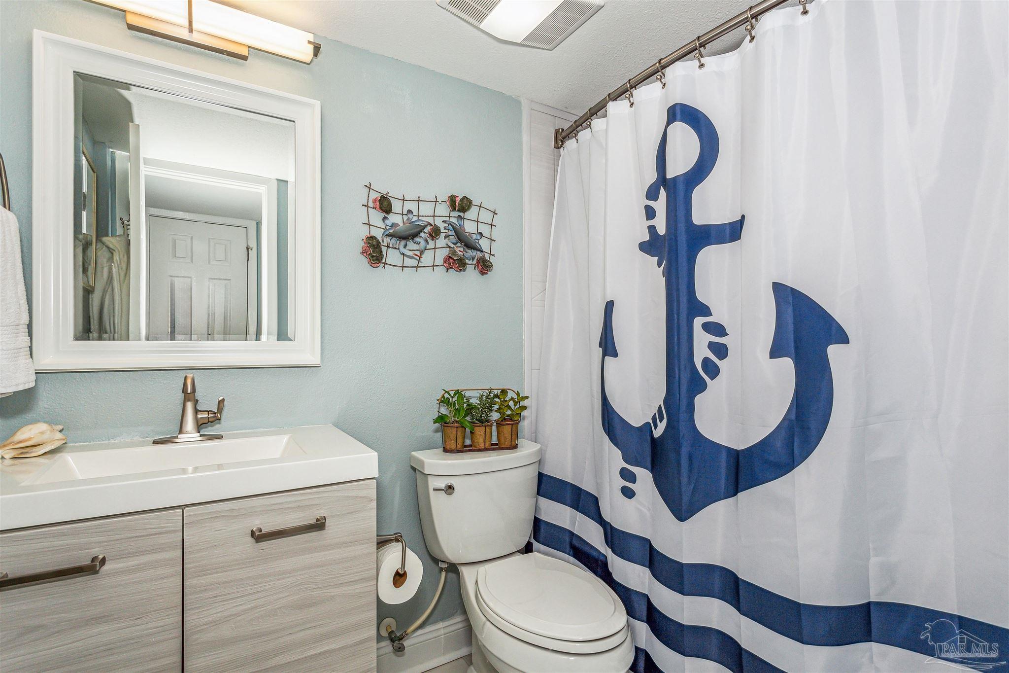 1390 Fort Pickens Road, Unit 116 Pensacola Beach, FL 32561 - Photo 29 of 37 a bathroom with a toilet sink vanity and mirror