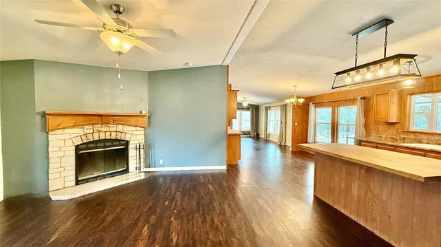 a view of a kitchen and an empty room with wooden floor