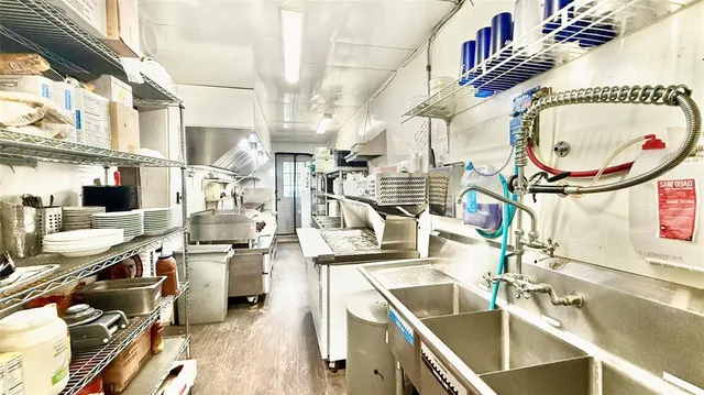 a living room with stainless steel appliances kitchen island granite countertop a table chairs and a view of living room