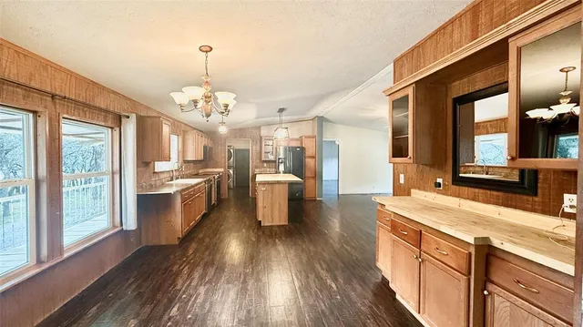 a large kitchen with kitchen island granite countertop lots of counter space a sink and appliances
