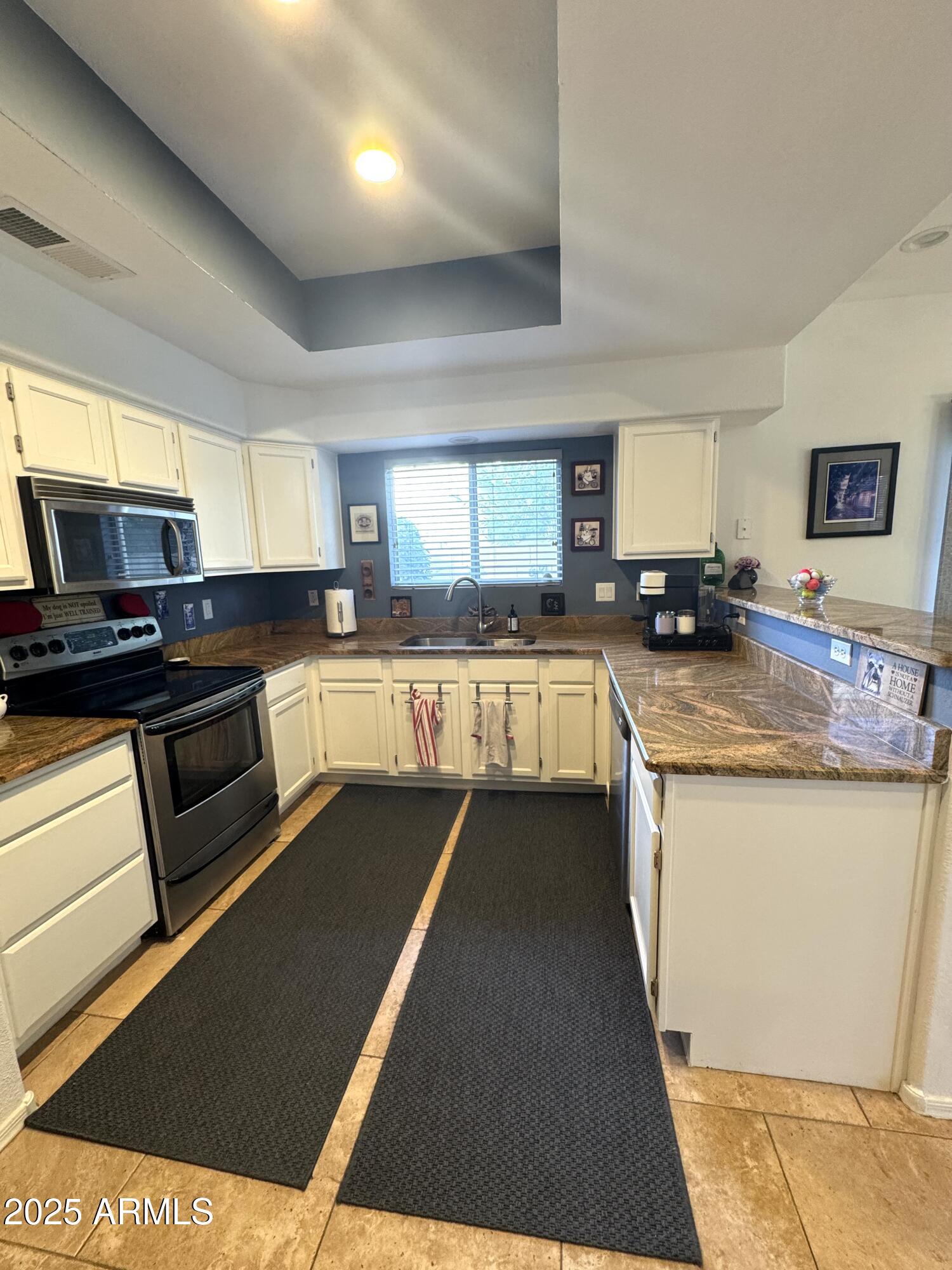 8833 South 51st Street, Unit 3 Phoenix, AZ 85044 - Photo 5 of 26 a kitchen with granite countertop a stove top oven a sink dishwasher and a microwave oven on the blue kitchen countertops